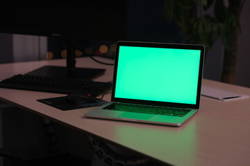 green screen laptop computer on table at night