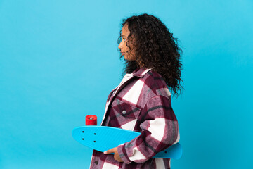 Teenager cuban girl isolated on blue background with a skate