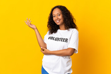 Teenager cuban volunteer girl isolated on yellow background extending hands to the side for...