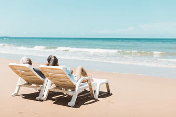 Retired couple resting on a adirondack chair by the beach in the sunlight and clean sandy beach. Retirement Planning Ideas and Happy Life.
