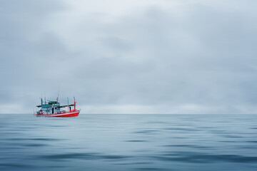 fishing boat floating in sea during strom coming with cloudy sky