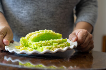 Sliced Pandan green cake with butter crumbs on a white plate.