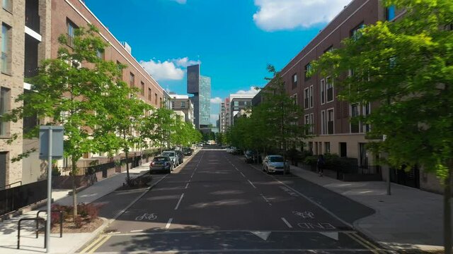 Fly through street between new or modernised buildings. Wide street with parking places and trees to reduce heat