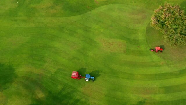 Golf course Aerial top view, Ride-on lawnmower operator cutting grass on golf course 