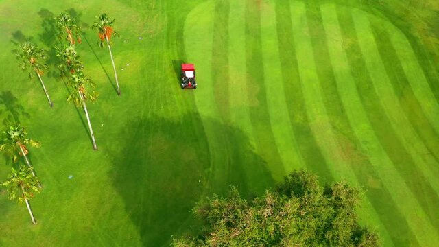 Golf course Aerial top view, Ride-on lawnmower operator cutting grass on golf course 