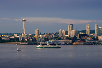 A sailboat and Washington State Ferry boat sail on Puget Sound as the famous Space Needle and skyscrapers rise above Elliott Bay in Seattle. - obrazy, fototapety, plakaty