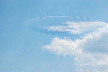 Sci-fi concept illustration. Unknown flying object silhouette hiding in blue sky and reflecting white cloud on surface with copy space © Rytis