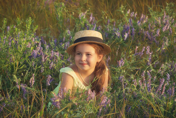 Portrait of a happy little girl in the field. A child in a straw hat on a summer walk.