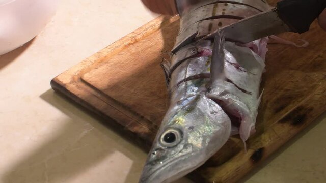 Chef Hands Cutting King mackerel on wheels on wooden board