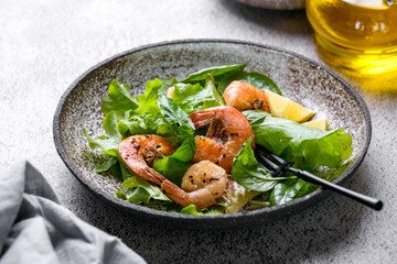 Fresh green salad with basil leaves, fried shrimps and lemon. Close up dish with copy space. Top view