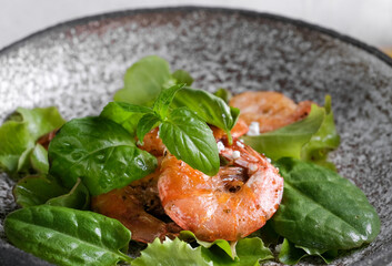 Fresh green salad with basil leaves, fried shrimps and lemon. Close up dish with copy space. Top view