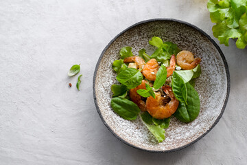 Fresh green salad with basil leaves, fried shrimps and lemon. Close up dish with copy space. Top view