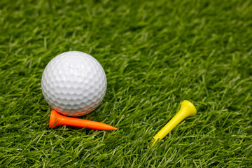 Golf ball with yellow and orange are on green grass