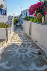Traditional cycladitic   alley with a narrow street,  whitewashed  houses and a blooming...