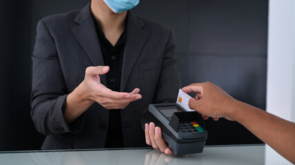 Male customer paying with credit card through terminal in restaurant store.