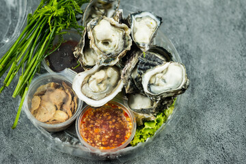 Fresh raw oysters and side dishes in Thai style with spicy dipping sauce