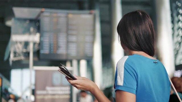 Female tourist checking boarding electronic schedule information at arrival departure board