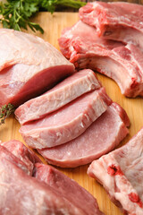 Slices of raw pork meat on wooden board, closeup