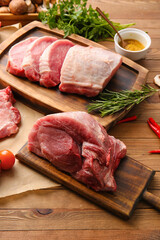 Boards with slices of raw pork meat and rosemary on wooden background