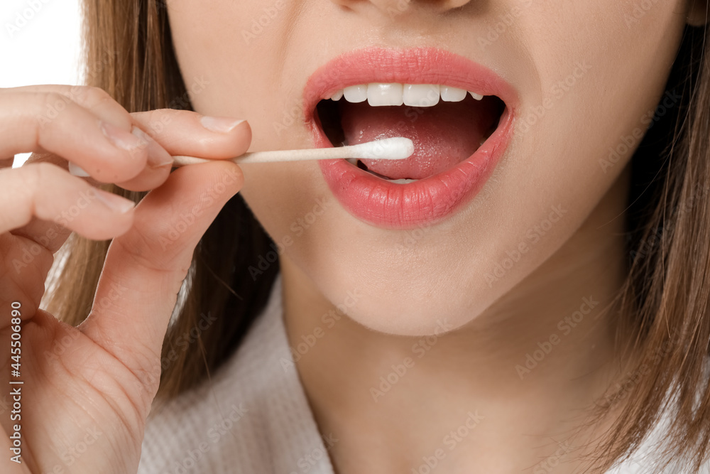 Wall mural young woman with cotton bud on white background, closeup