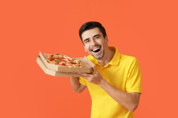 Happy young man with tasty pizza on color background