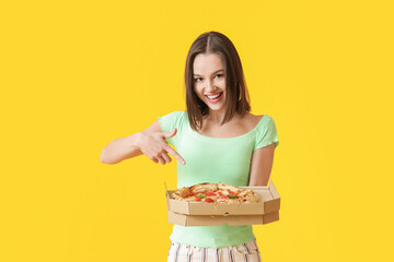 Beautiful young woman pointing at tasty pizza on color background