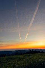 Fototapeta na wymiar Beautiful bright orange sunrise/sunset over a hilly landscape in Switzerland
