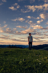 Young man at sunrise sunset in front of mountain landscape