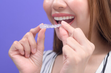 Young smiling woman holding invisalign braces in studio, dental healthcare and Orthodontic concept..