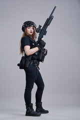A young woman with a machine gun in her hands on a gray background