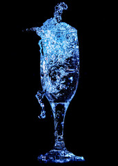Splashes and drops of water in a glass are isolated on a black background.