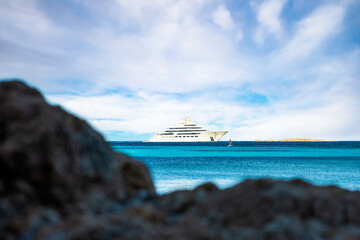 (Selective focus) Stunning view of a luxury yacht sailing on a turquoise water while a defocused...