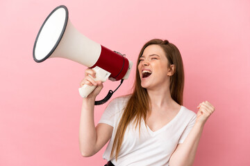 Teenager girl over isolated pink background shouting through a megaphone to announce something in...