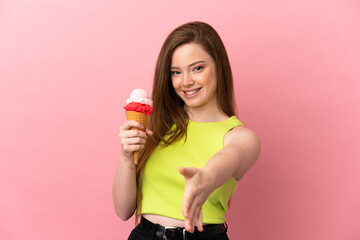 Teenager girl with a cornet ice cream over isolated pink background shaking hands for closing a good deal