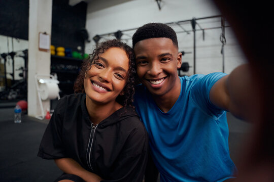 Mixed race friends taking a photo together in the gym. Happy African American male and female taking a selfie. High quality photo