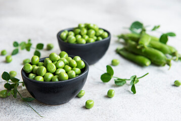 Fresh green peas pods and green peas with sprouts on concrete background.