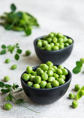 Fresh green peas pods and green peas with sprouts on concrete background.
