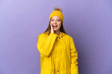 Teenager girl wearing a rainproof coat over isolated purple background with surprise and shocked facial expression