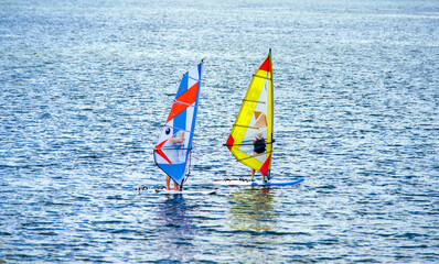 Two windsurfers swim on the sea surface