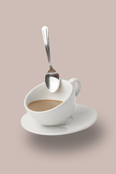 Levitation of Cup of Coffee with a spoon. White mug flying on the air on pastel beige background. Minimal concept