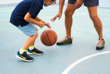 Fototapeta premium A happy little boy is playing basketball with his grandfather.