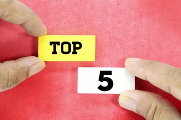 hand holding a wooden cube with the word Top 5