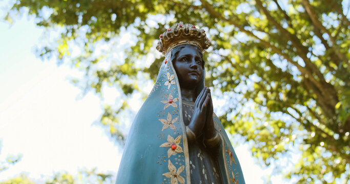 Sculpture of the image of "Nossa Senhora Aparecida" the patroness of Brazil. Image with gimbal on nature background on sunny day.