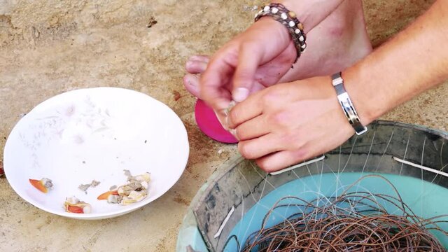 Hands preparing a fishing trap, Fishing trap prepared with the hands with the bracelets. Bare foot fisherman preparing a fishing trap.