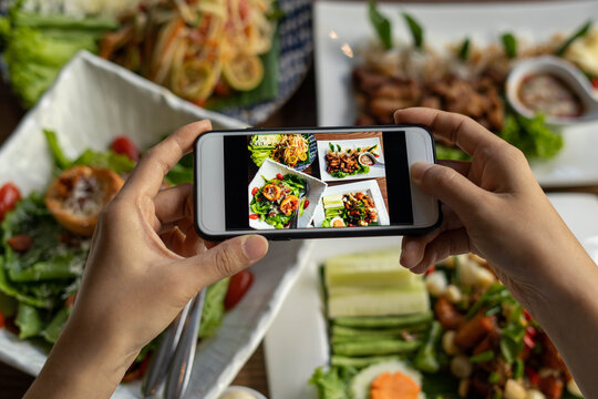 The restaurant owner takes a picture of the food on the table with a smartphone to post on a food website. Online food delivery and ordering service