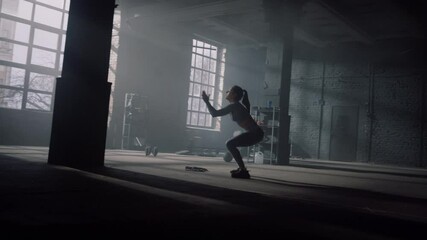 Girl training body in sport club. Athlete doing high jumps with squats 