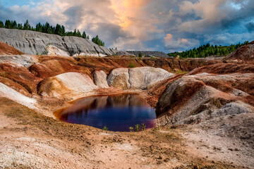 Landscape like a planet Mars surface. Ural refractory clay quarries. Nature of Ural mountains, Russia. The hardened red-brown surface of the earth. Red lake, blue sky, beautiful clouds