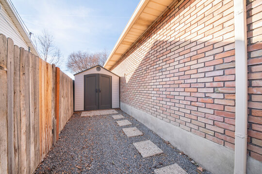 Vinyl shed in between a wooden fence and brick walls of a house