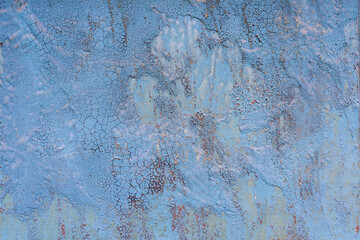 A close-up of a surface with swollen and cracked old blue paint. There are irregularities and sagging. Background. Texture.