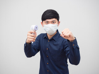 Man wearing protect mask stance and holding infrared thermometer with serious face portrait white...